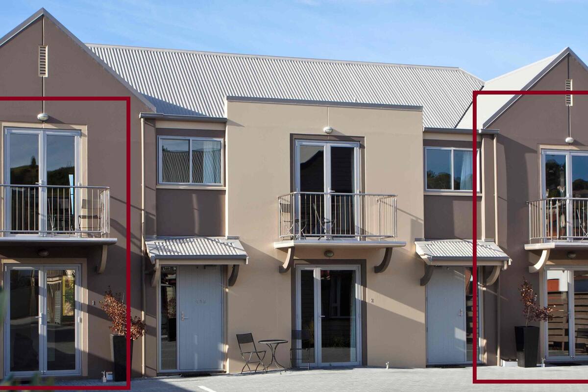 A row of three-story buildings with balconies, large windows, and a flat roof.