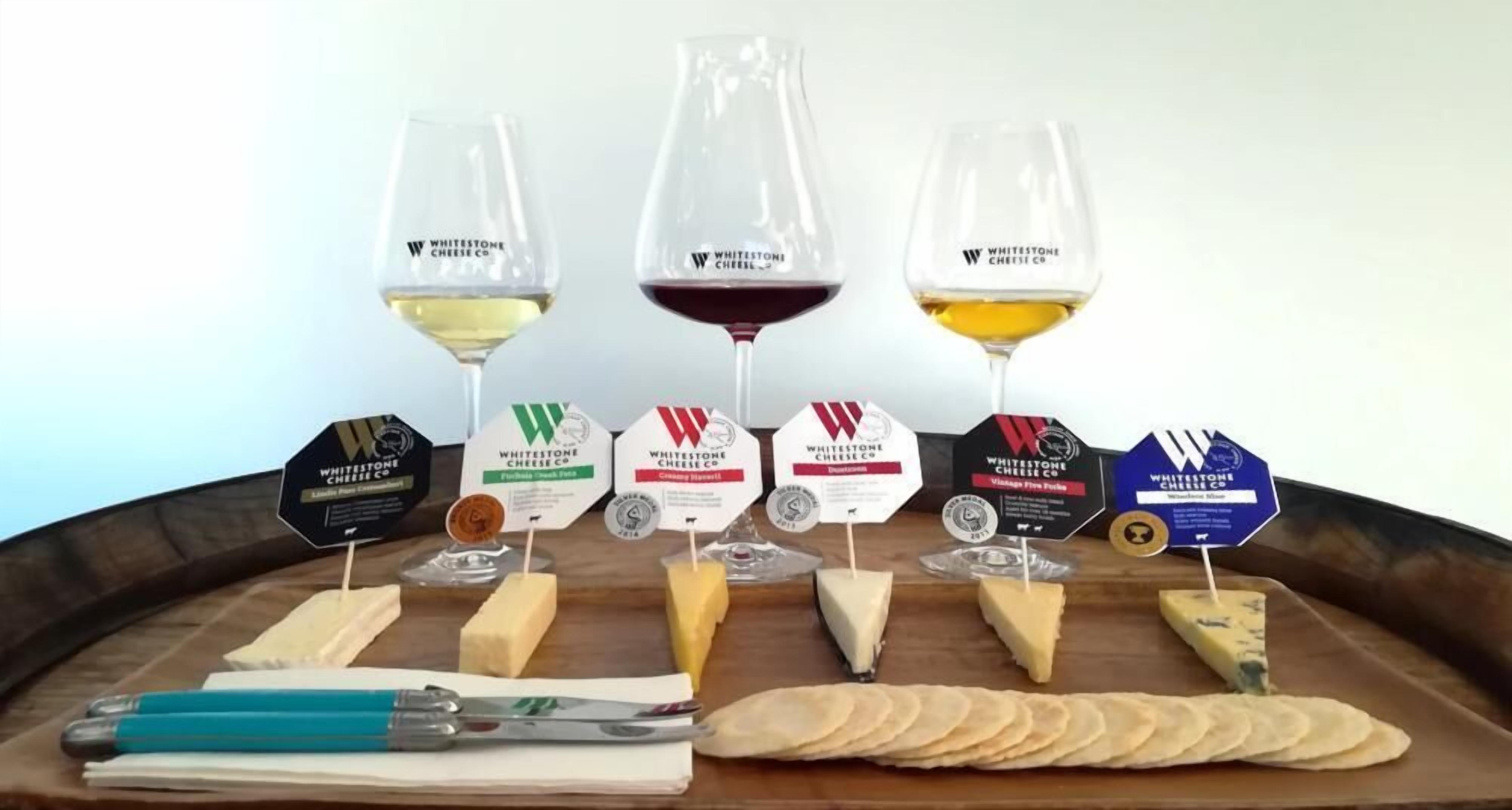 A cheese tasting setup with various cheeses and glasses of wine.