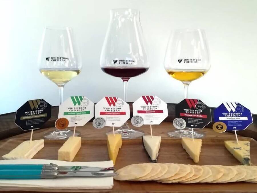 A cheese tasting setup with various cheeses and glasses of wine.