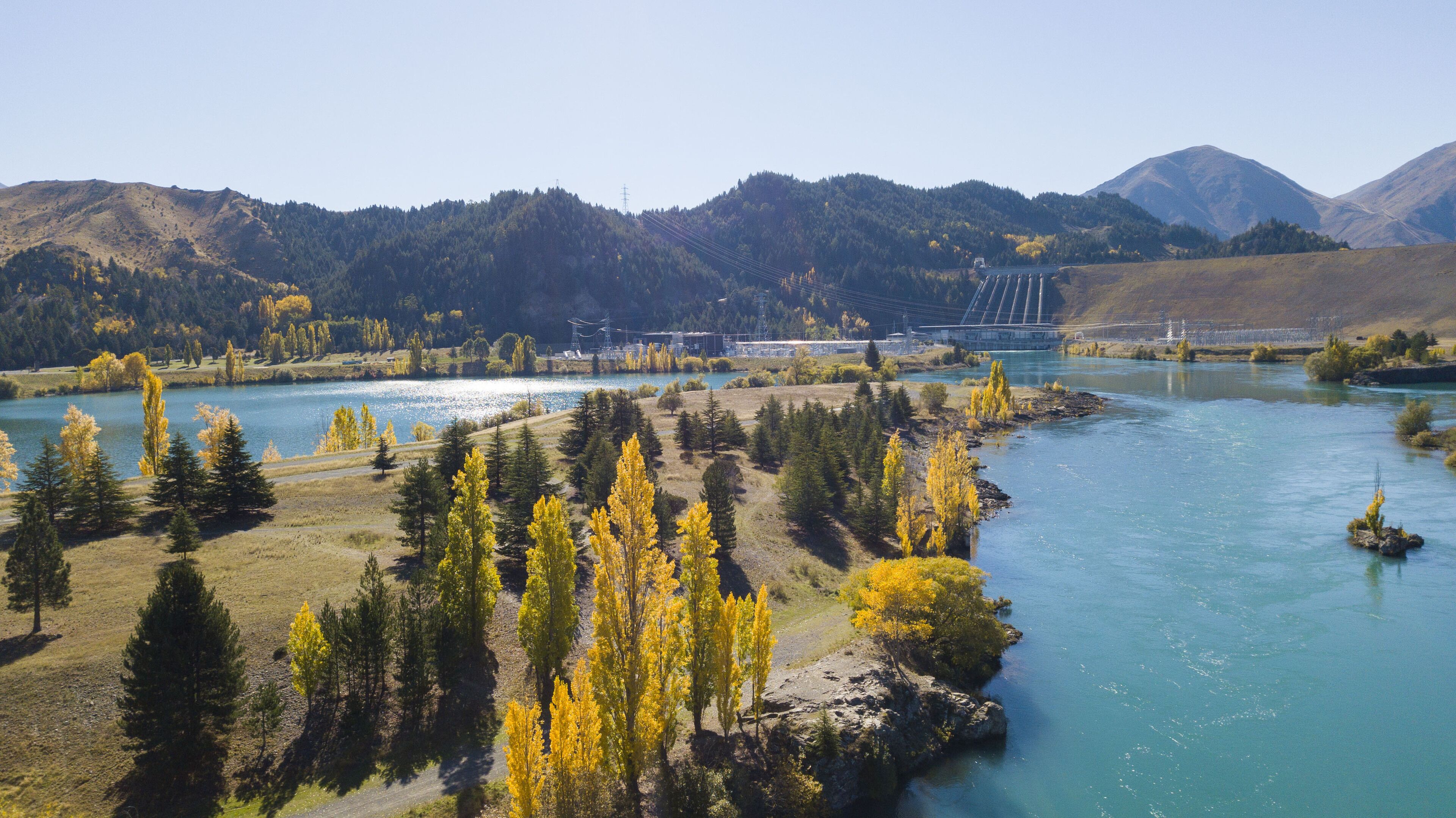 Un río con un puente, rodeado de montañas y árboles.