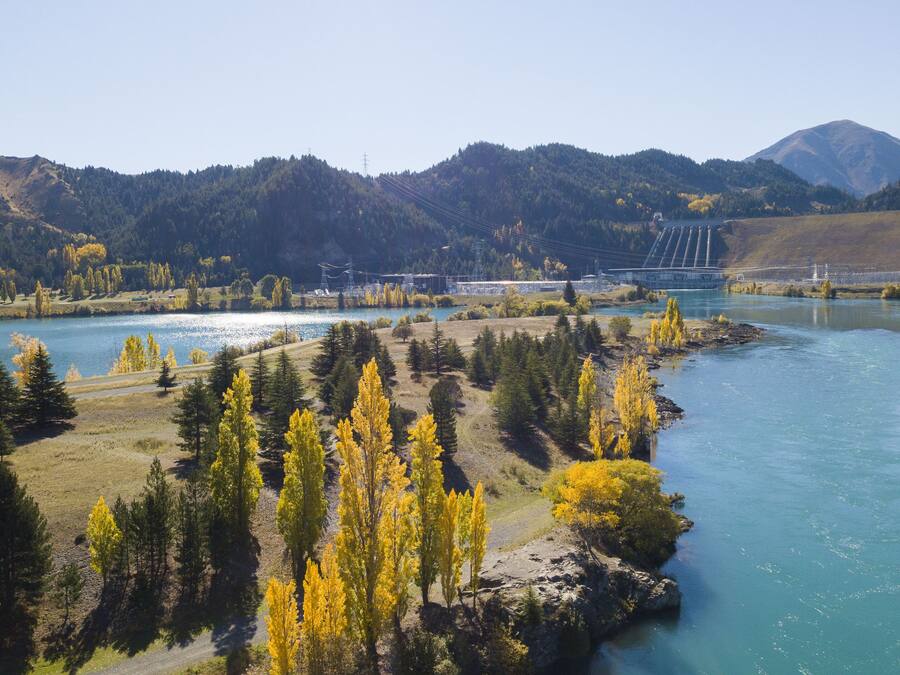 Un río con un puente, rodeado de montañas y árboles.