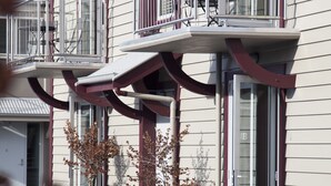 Un edificio de varios pisos con balcones, mobiliario exterior y ventanas grandes.