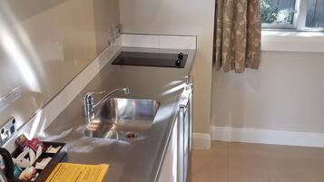 A modern kitchen with a stainless steel sink, a built-in oven, and a window with curtains.
