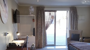 Habitación de hotel con escritorio, silla, cama y kitchenette.