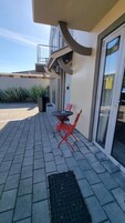 Un espacio al aire libre con mesa y sillas, una puerta y una ventana.