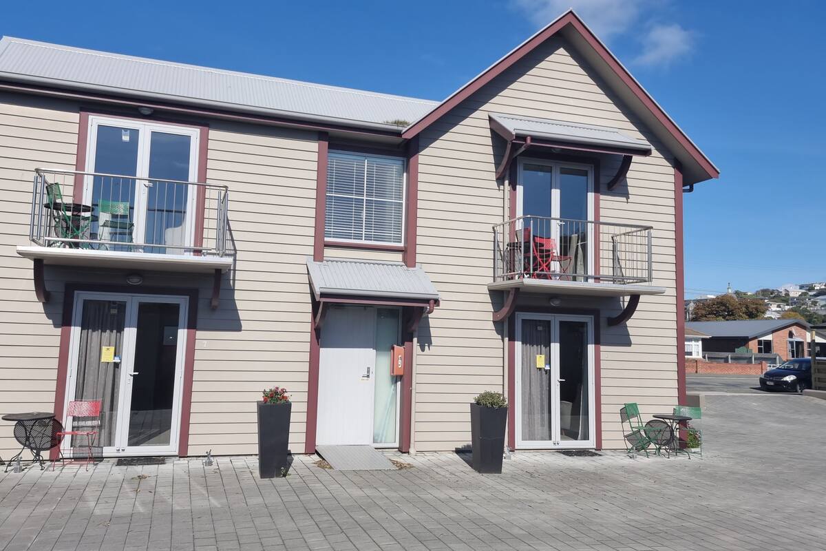 A two-story building with a balcony on the first floor, a door with a small porch, and a garage door.