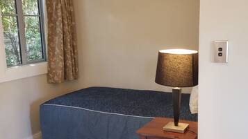 Une chambre à coucher avec un lit, une lampe, un radiateur et une fenêtre avec des rideaux.