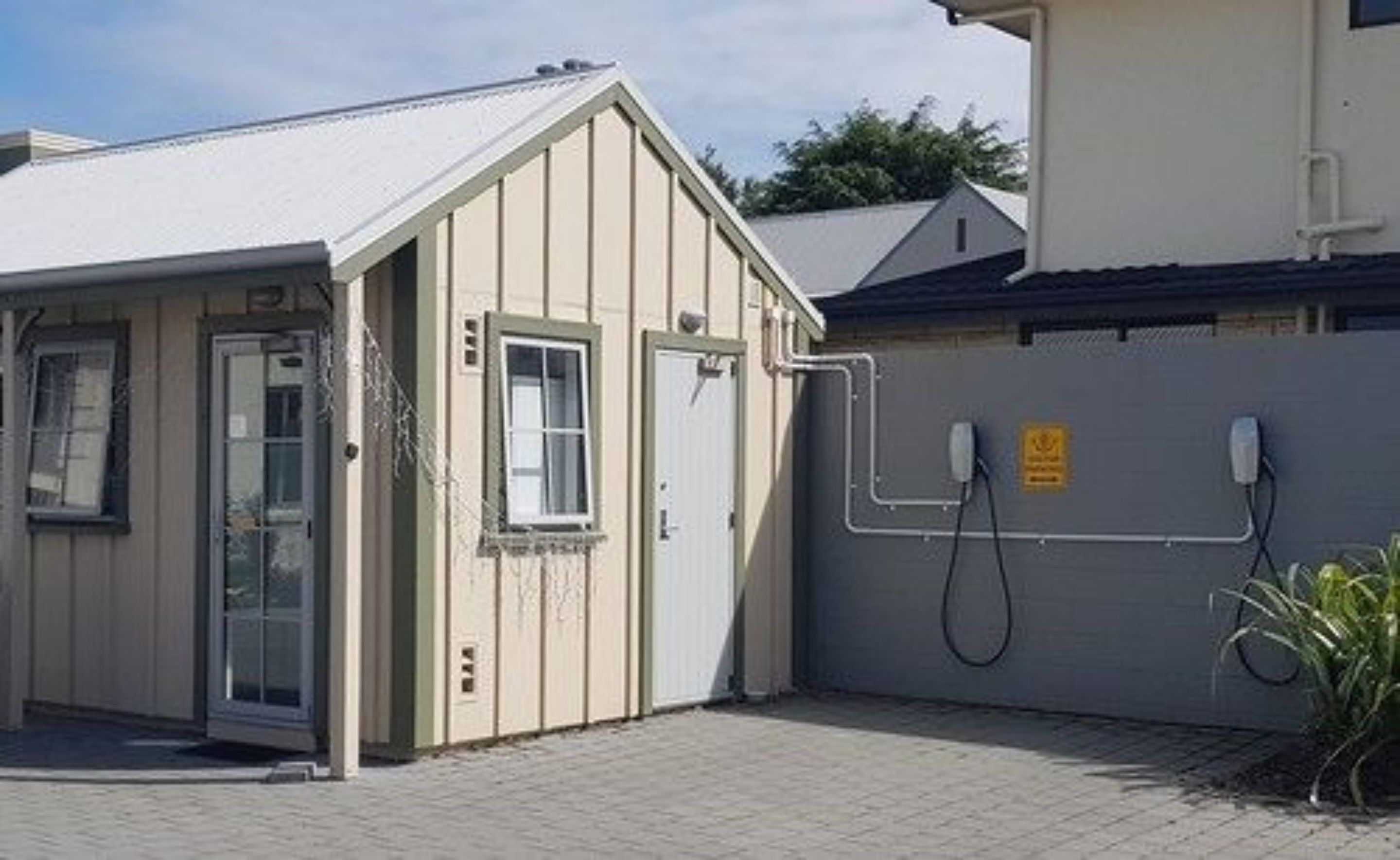 Um pequeno edifício térreo com fachada bege, uma porta e uma janela.