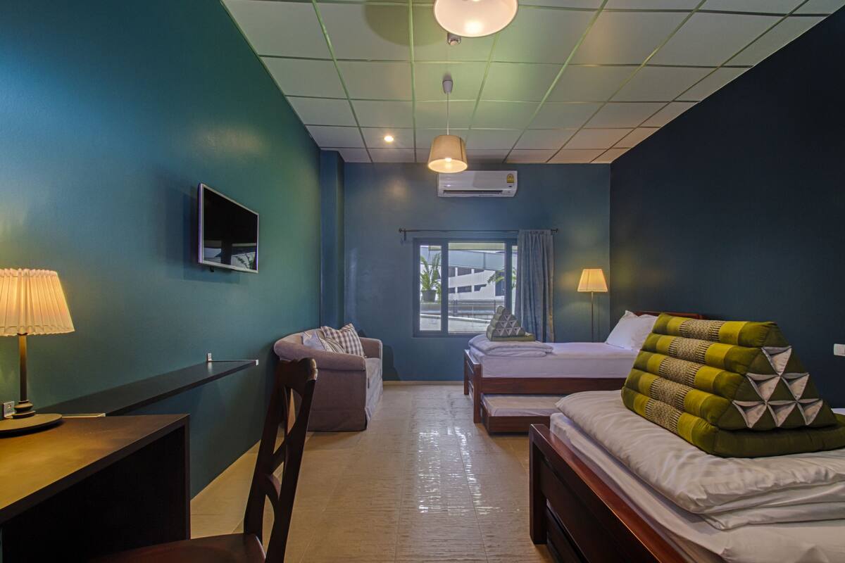 A hotel room with a bed, a desk, a chair, a TV, and a window.