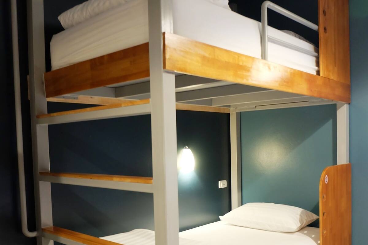 A bunk bed with a wooden frame and white bedding.