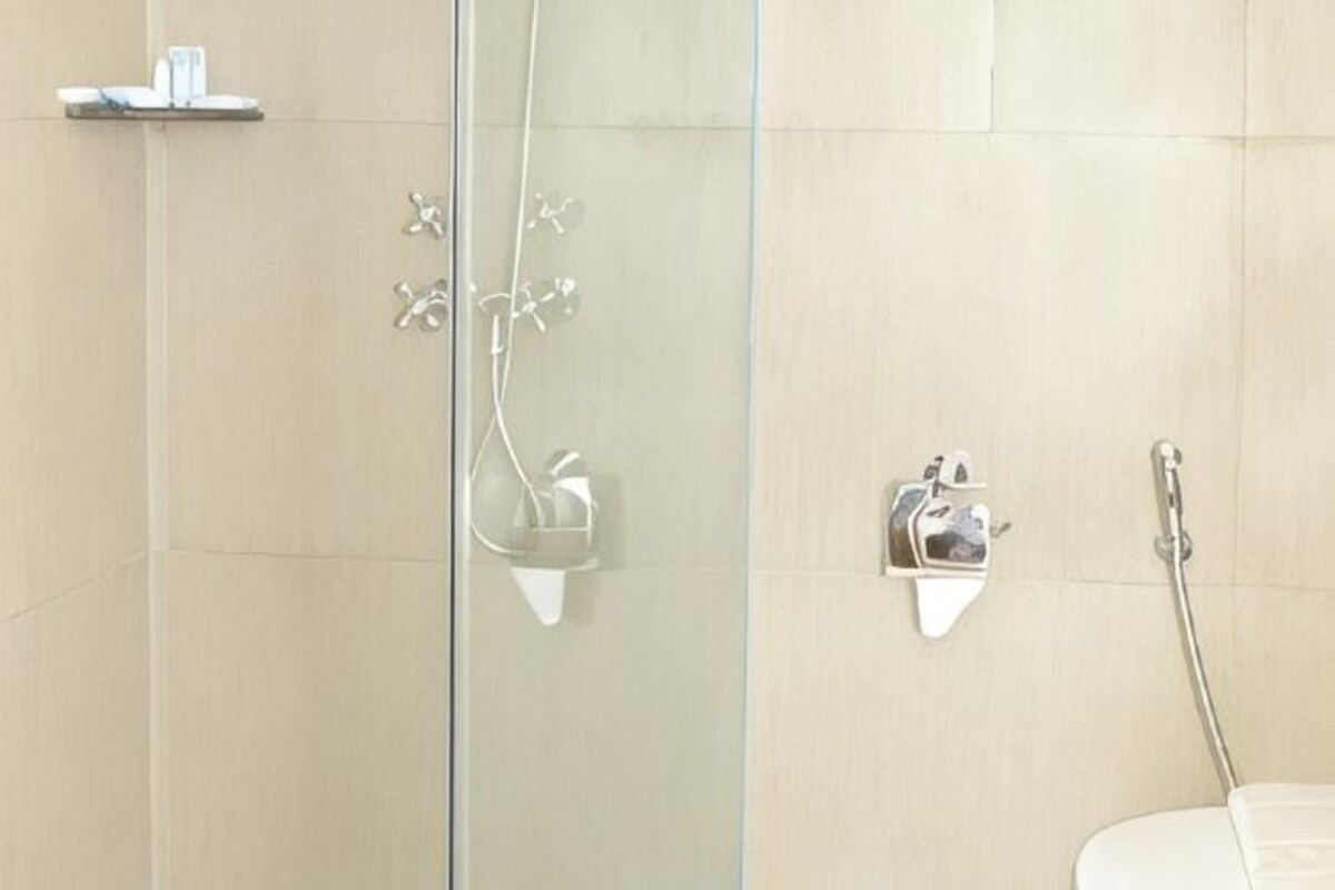 Een badkamer met een douchecabine van glas, een toilet en een wastafel met spiegel.