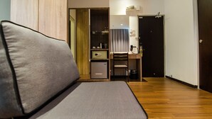 A modern hotel room with a sofa, a compact kitchenette, a small fridge, and a door leading to another room. - Mornington Hotel Soon Choon (Ipoh)