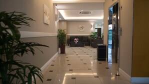 Rebedor d'hotel amb un sòl polit, un sofà, una taula de centre i plantes en testos.