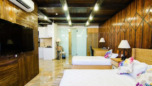 Habitació d'hotel amb un llit gran, televisió, escriptori i un bany visible a través d'una porta de vidre.