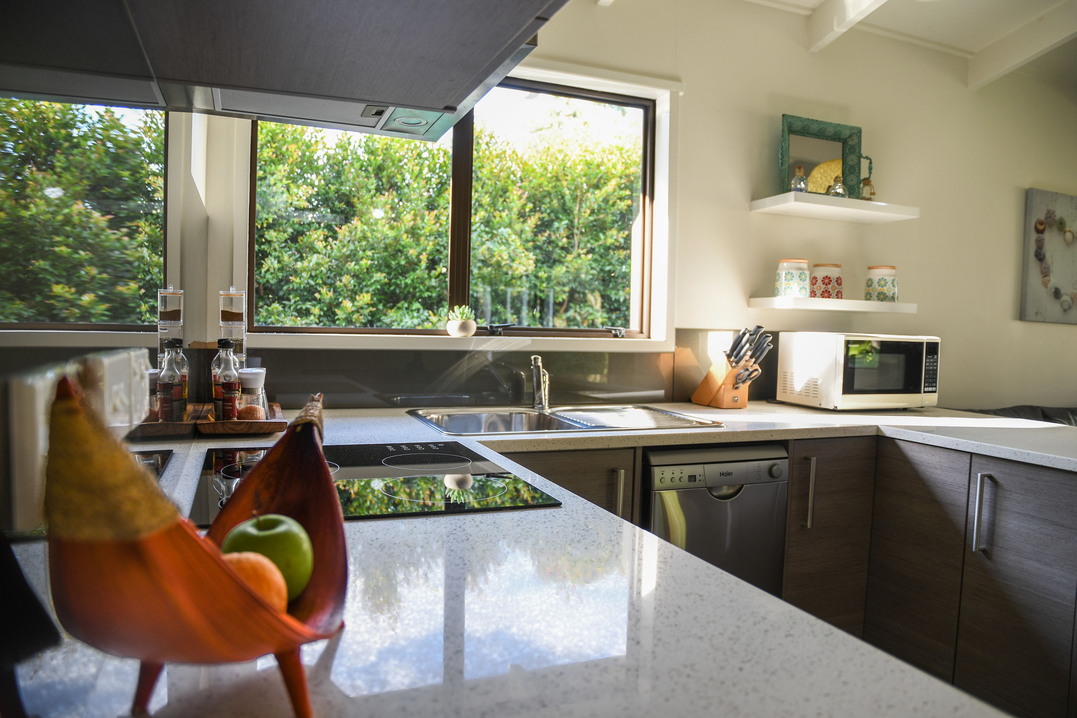A modern kitchen with a large window, a microwave, and a sink.