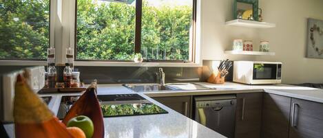 A modern kitchen with a large window, a microwave, and a sink.