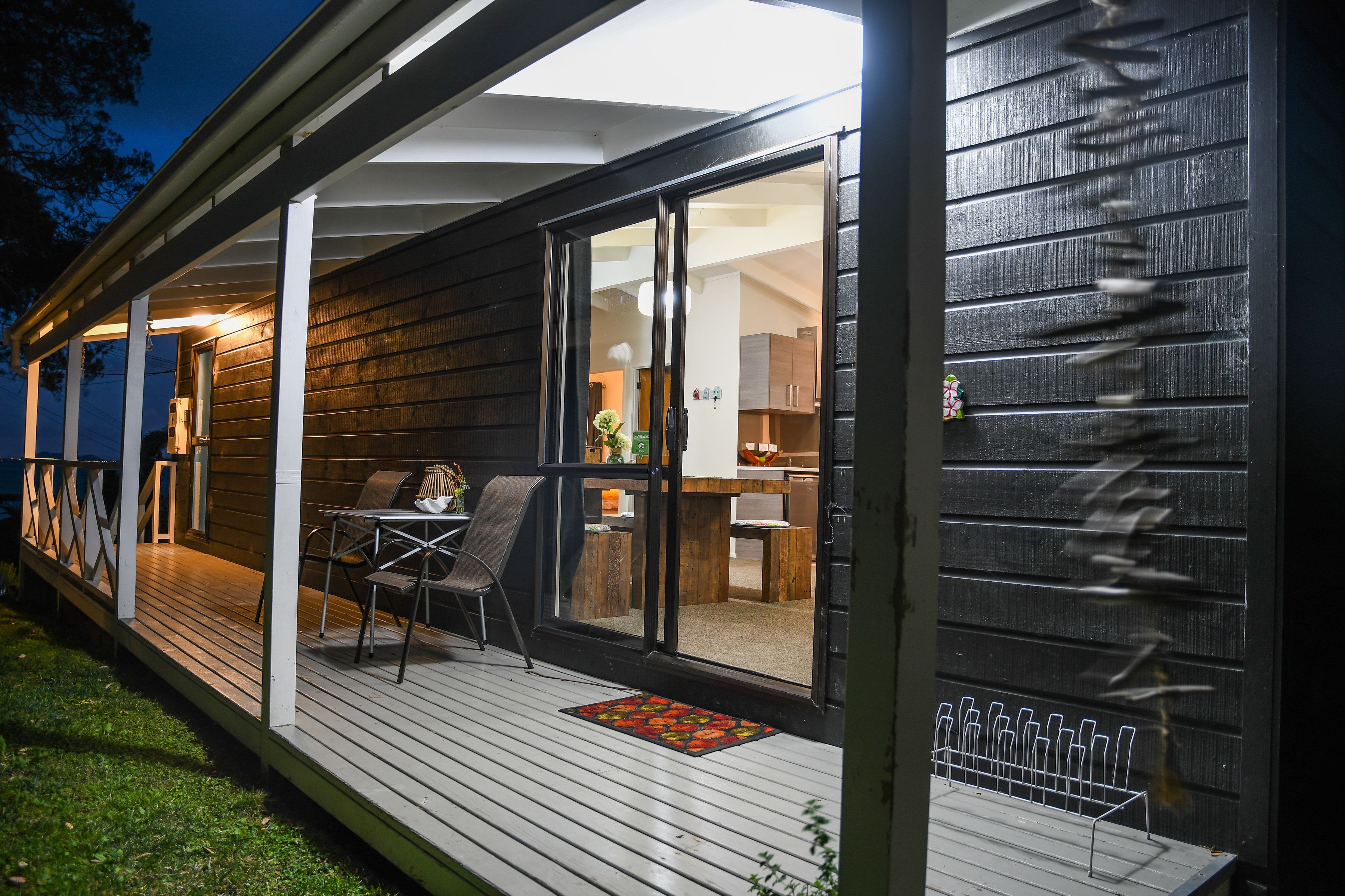 A wooden deck with a dining area, a covered patio, and a view into the house.