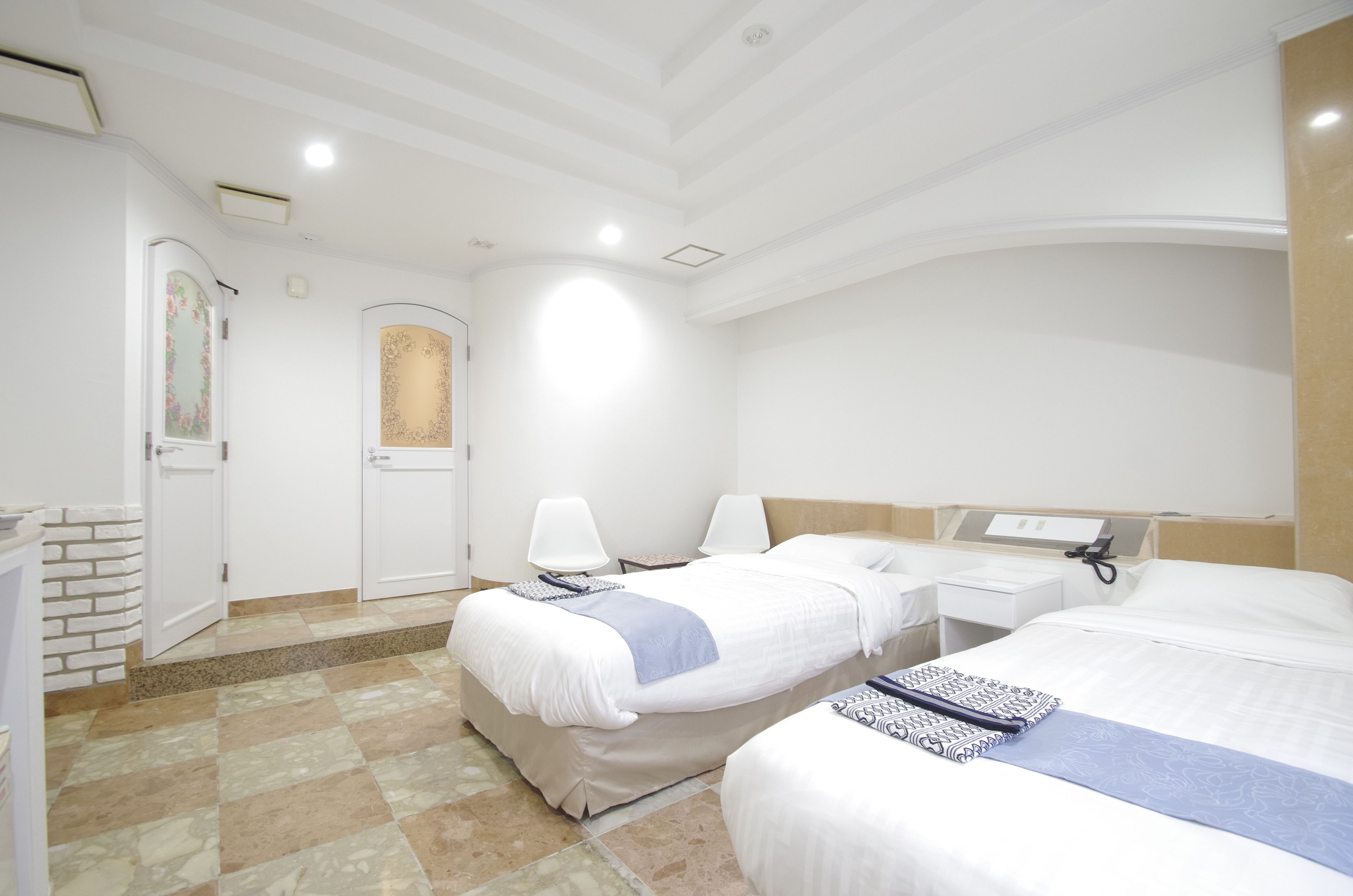 Hotelkamer met twee bedden, een bureau, een stoel en een badkamer met douche en toilet.