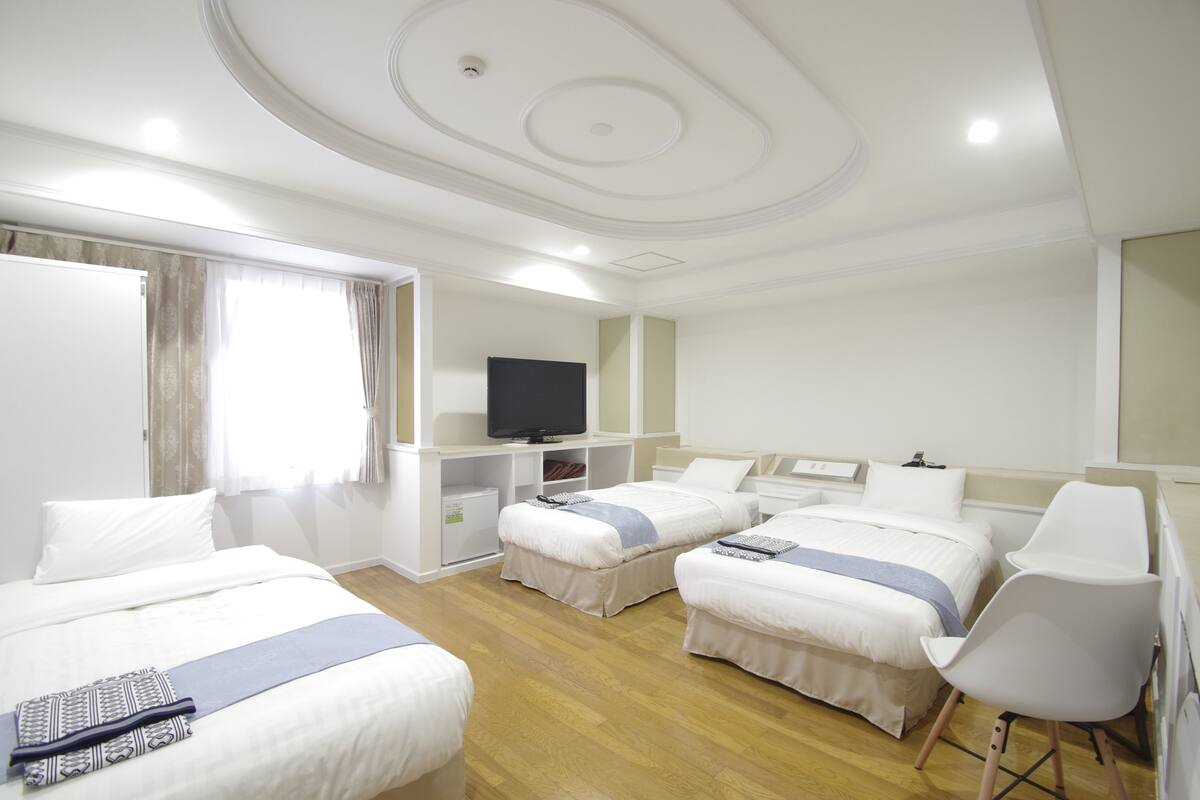 Una camera d'albergo con due letti, una televisione, una scrivania e una sedia.