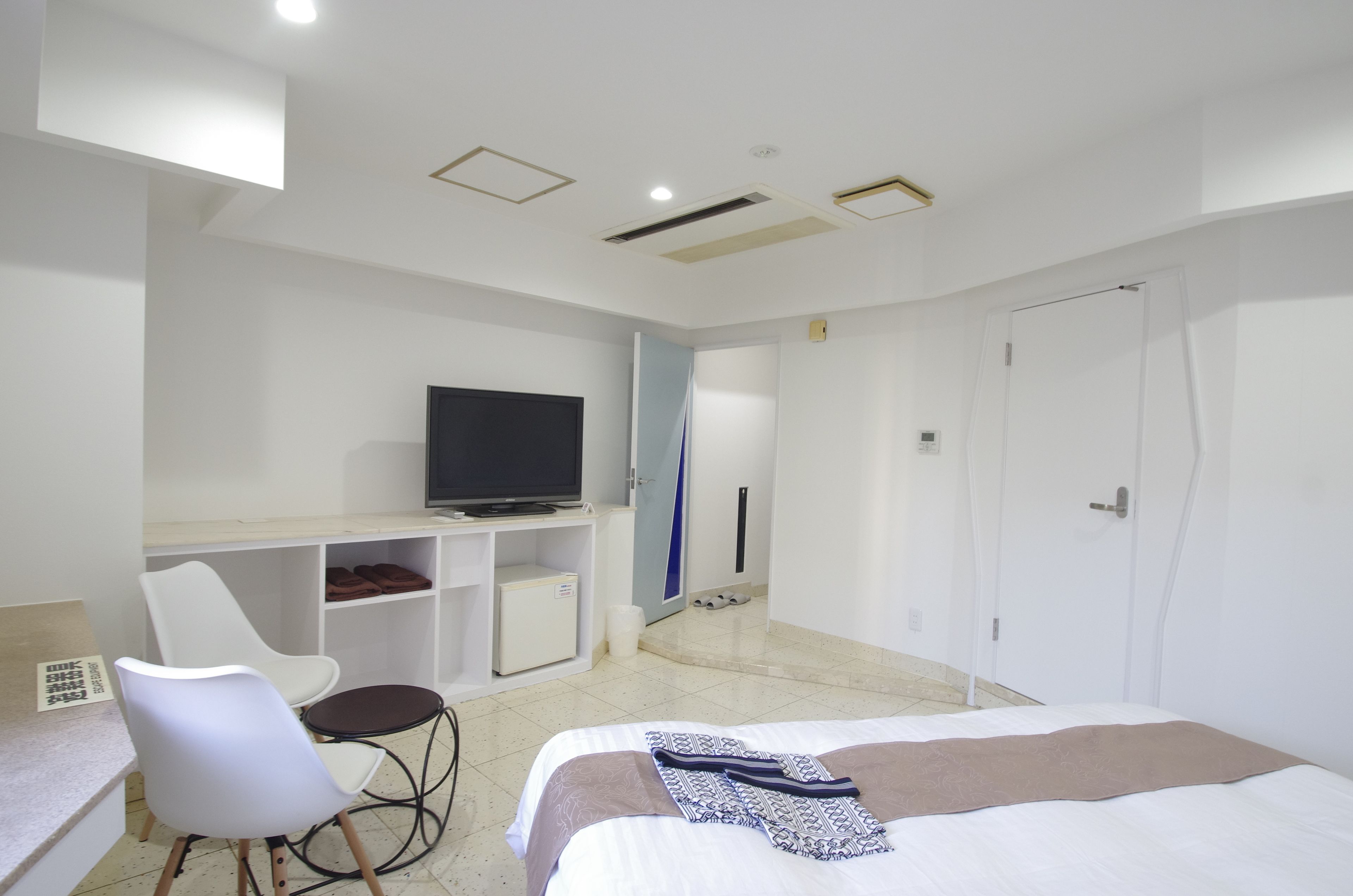 Una habitación de hotel con cama, escritorio con televisor, silla y armario.