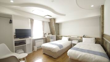 Une chambre d’hôtel avec deux lits, un bureau, une télévision et un coin salon.