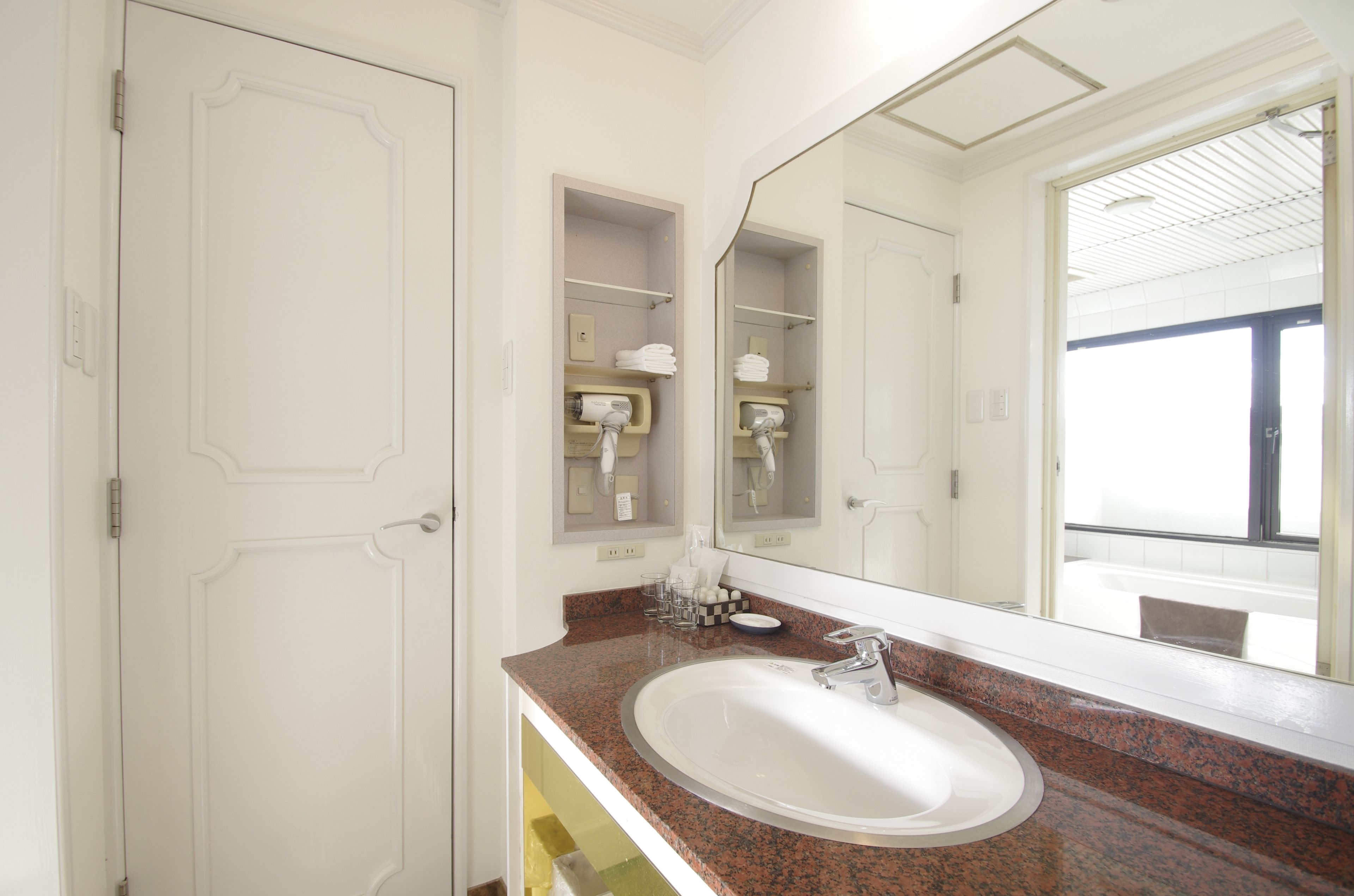 A bathroom with a white sink, granite countertop, and a large mirror.