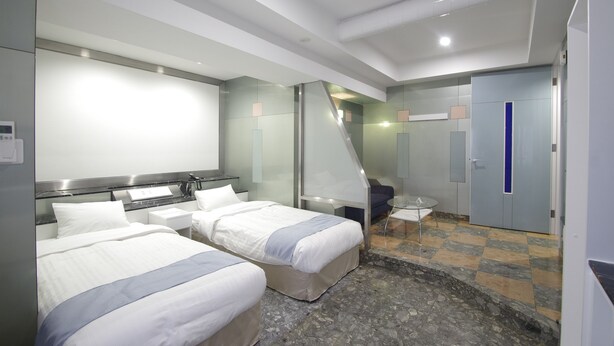 A hotel room with two beds, a small table, a mirror, and a wardrobe. - Hotel Imalle Yokohama Isezakicho - Hostel (Yokohama)