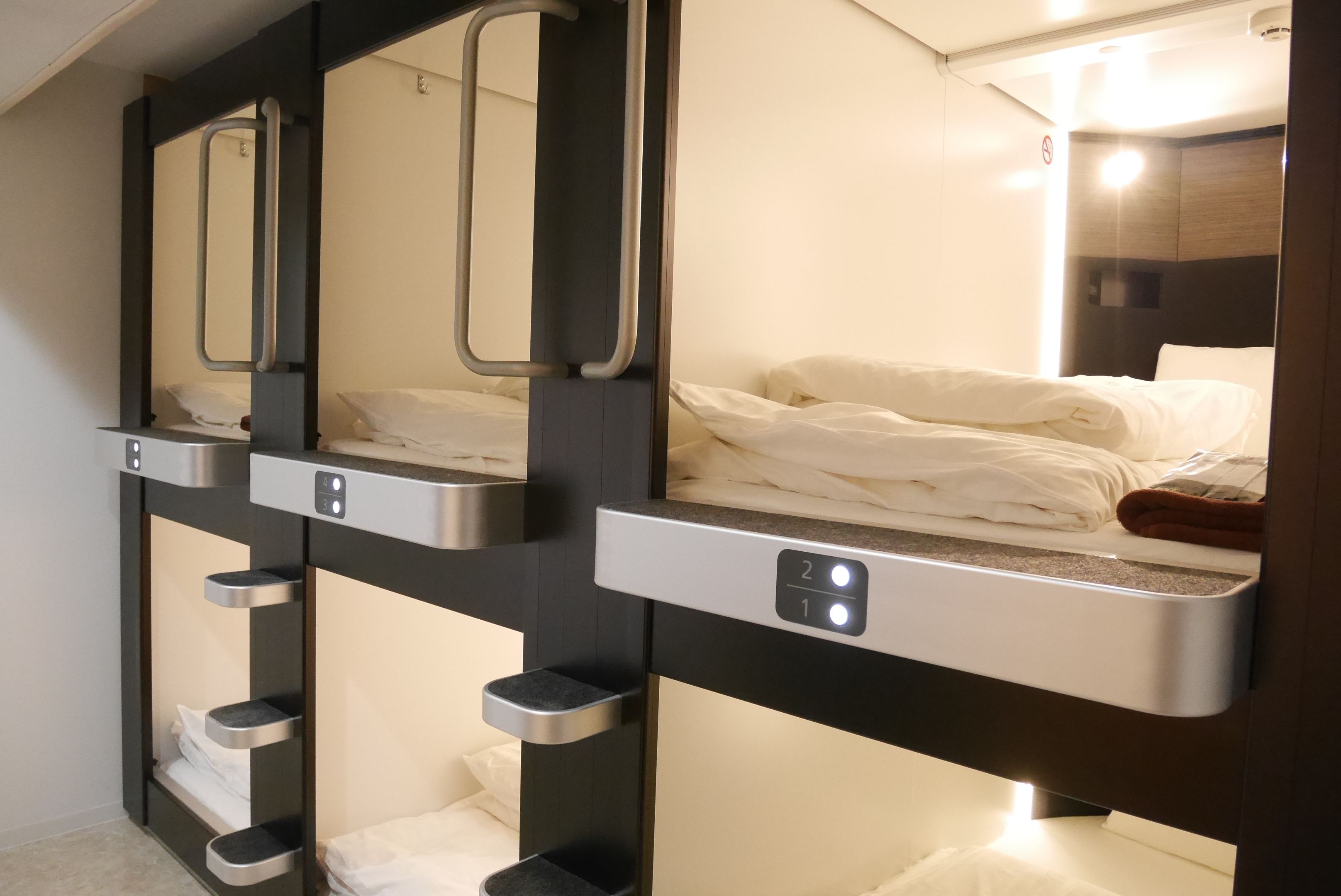 A row of bunk beds with individual control panels, each with a small shelf below.