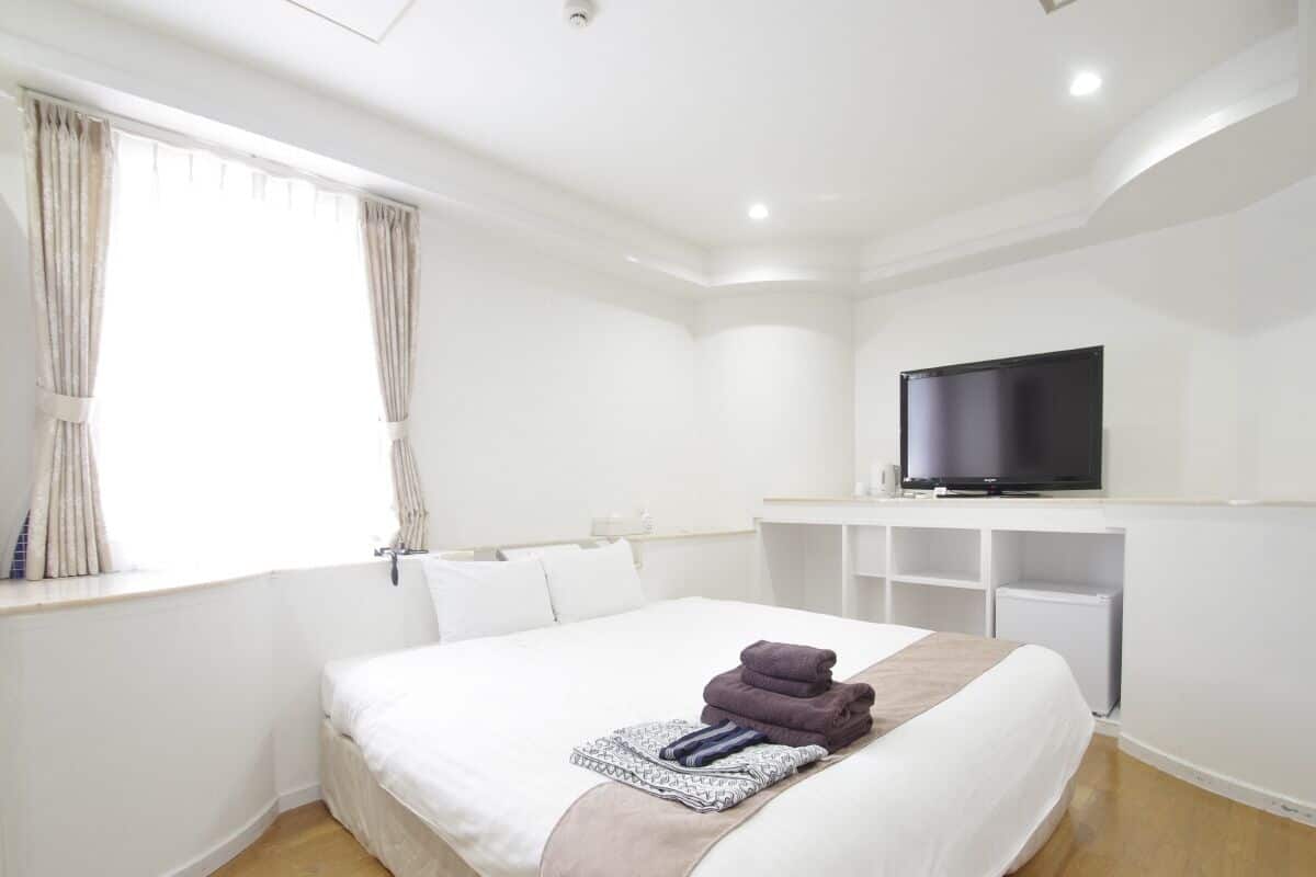 Una camera d'albergo con un letto grande, una televisione e una finestra con tende.
