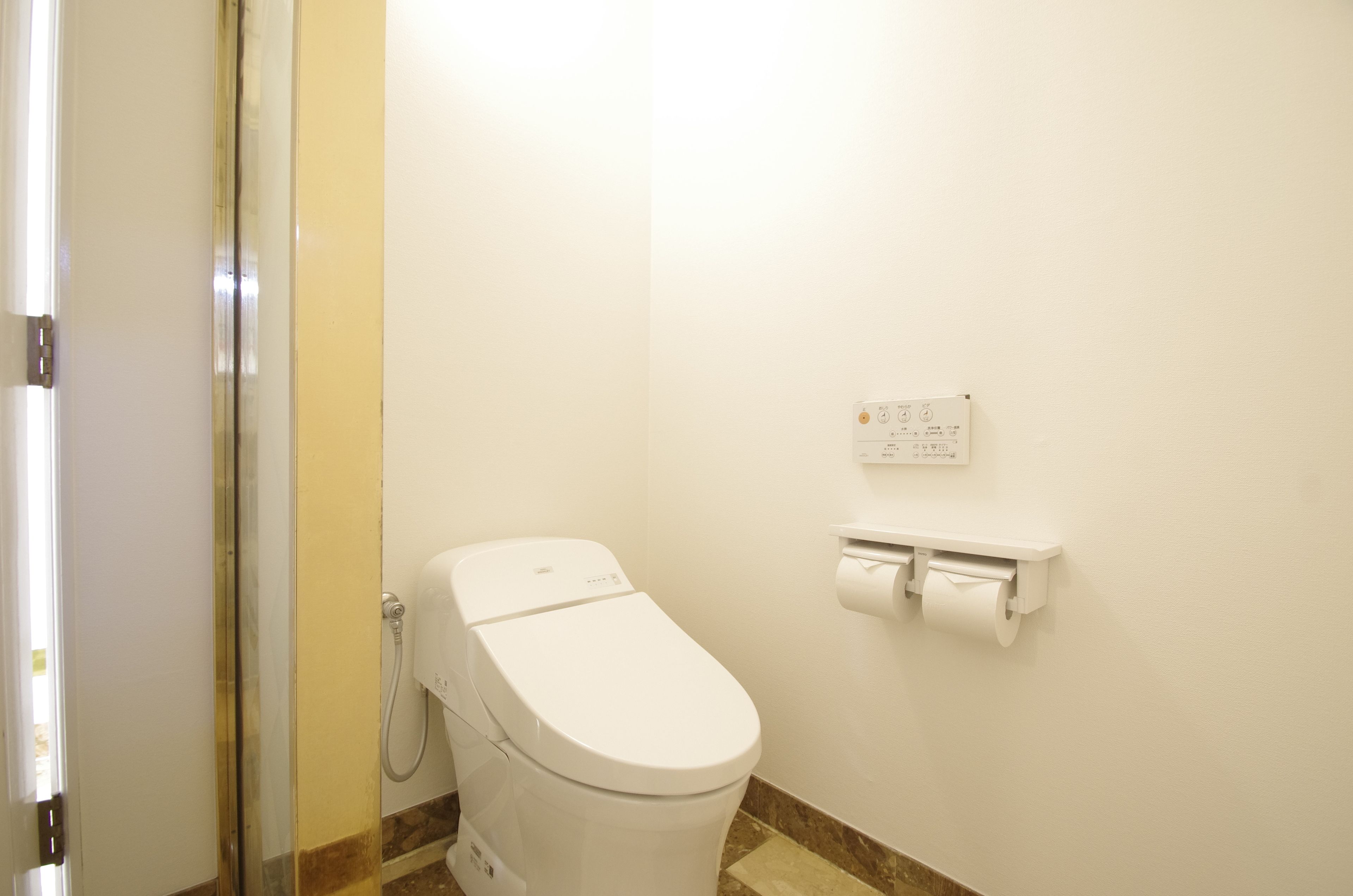 A small, clean bathroom with a toilet, a paper towel dispenser, and a wall-mounted sign.