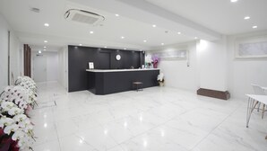 A modern reception area with a black counter, white marble flooring, and a clock on the wall. - Hotel Imalle Yokohama Isezakicho - Hostel (Yokohama)