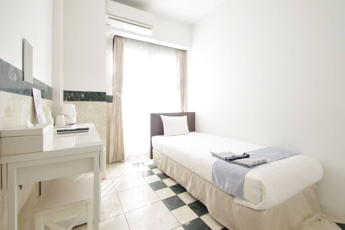 Una camera d'albergo con un letto, una scrivania e un condizionatore d'aria.