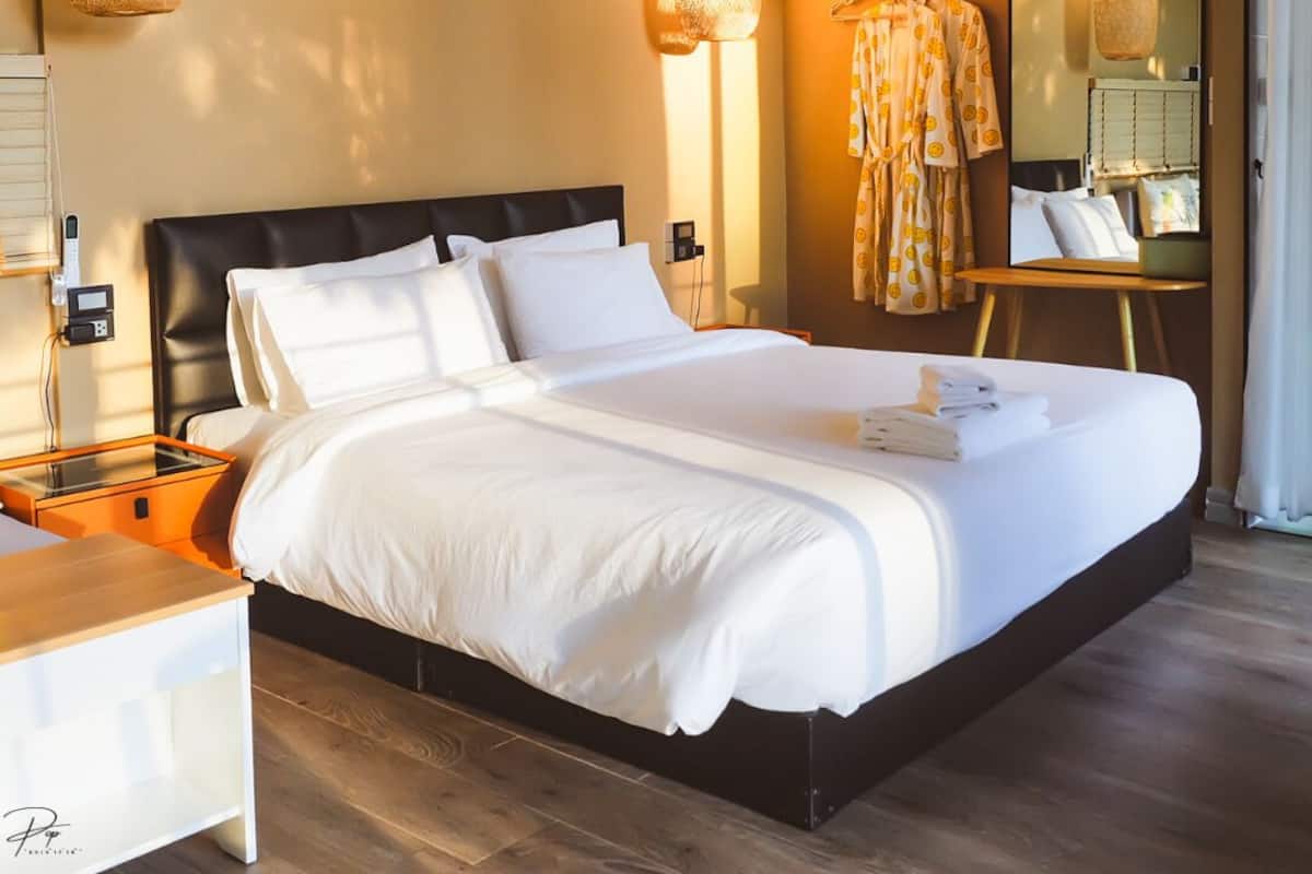 Ett modernt hotellrum med en stor säng, sängbord, en spegel och hängande lampor.