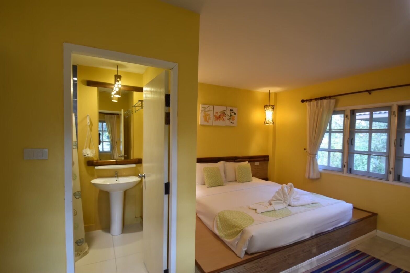 A hotel room with a bathroom, a bed, and a window.