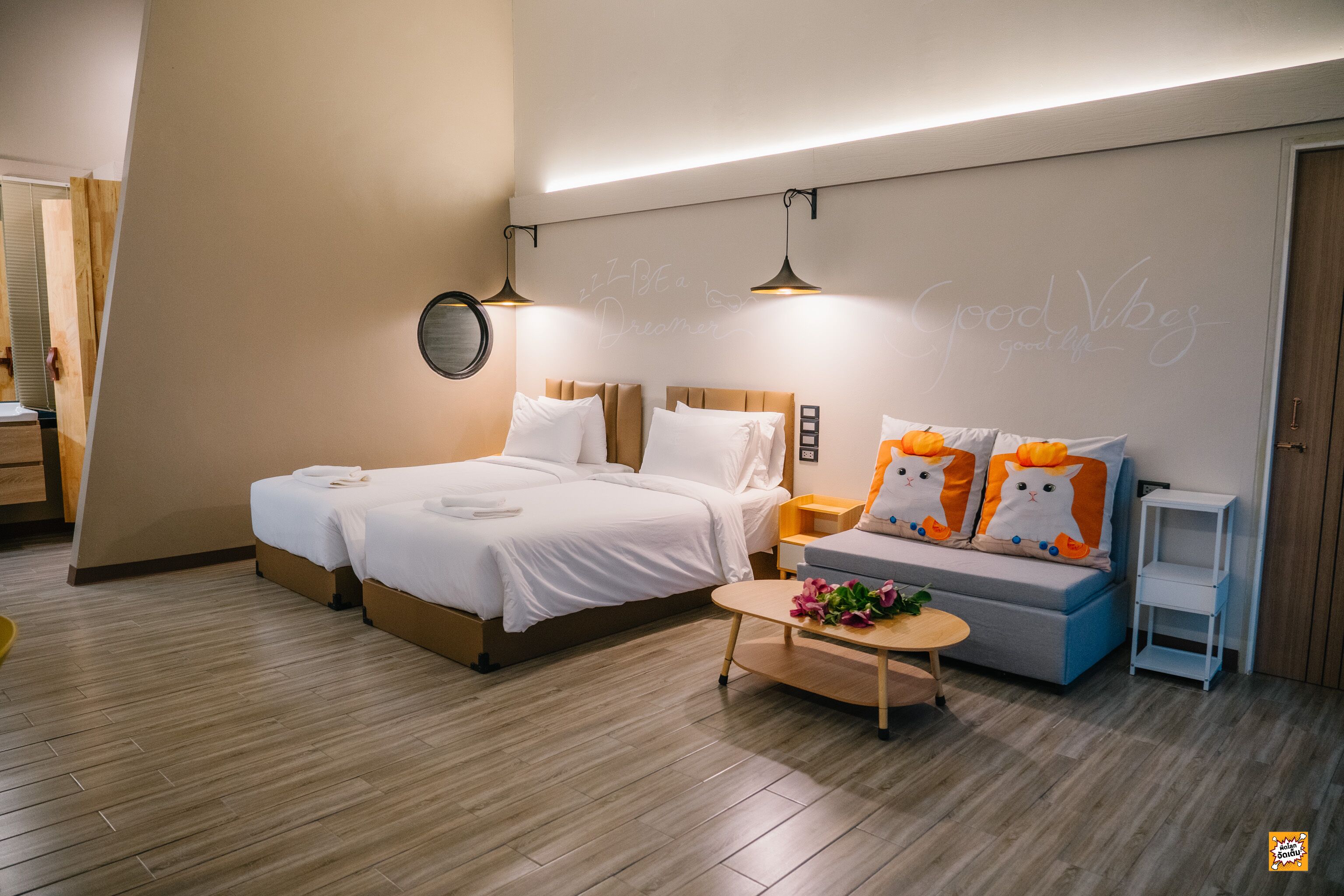 Una habitación de hotel moderna con una cama, un sofá, una mesita de café y una pared con citas motivacionales.