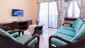A living room with a television, a sofa, two chairs, a coffee table, and a window with curtains. -  Istana Residences Langkawi (Langkawi)