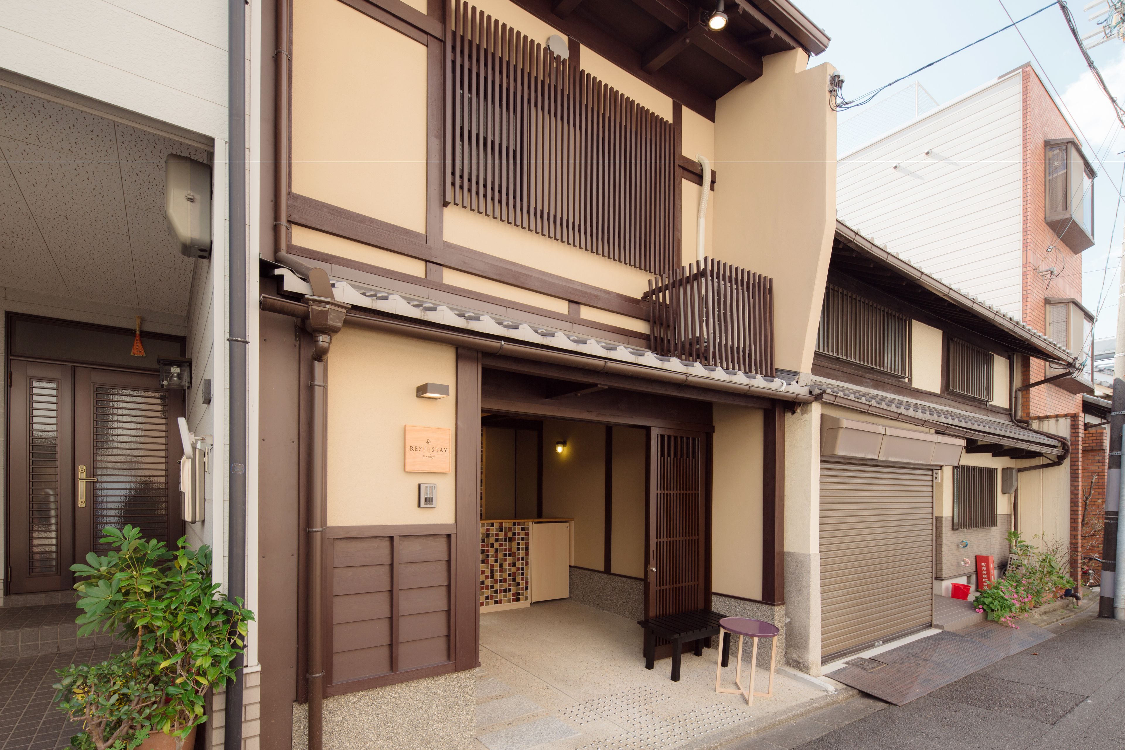 Un bâtiment de style japonais traditionnel, doté d’une porte coulissante à l’entrée, d’un petit espace extérieur aménagé en coin salon et d’une pancarte indiquant une chambre « RÉSERVÉE ».