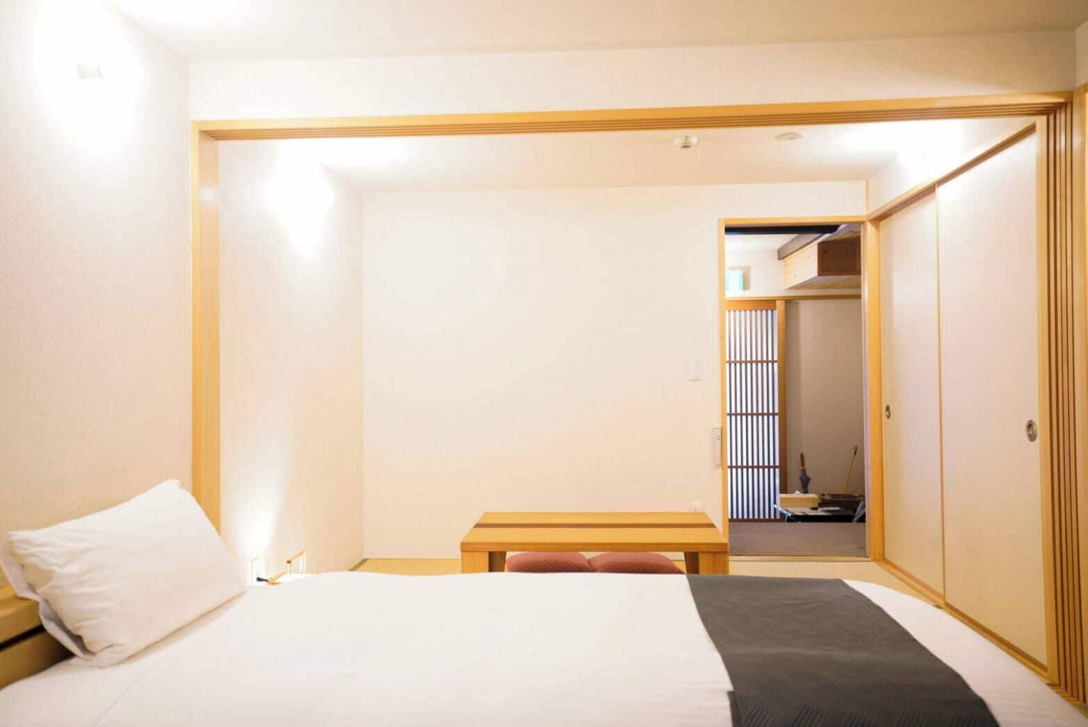 A hotel room with a bed, a bedside table, and a wardrobe.