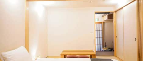 A hotel room with a bed, a bedside table, and a wardrobe.