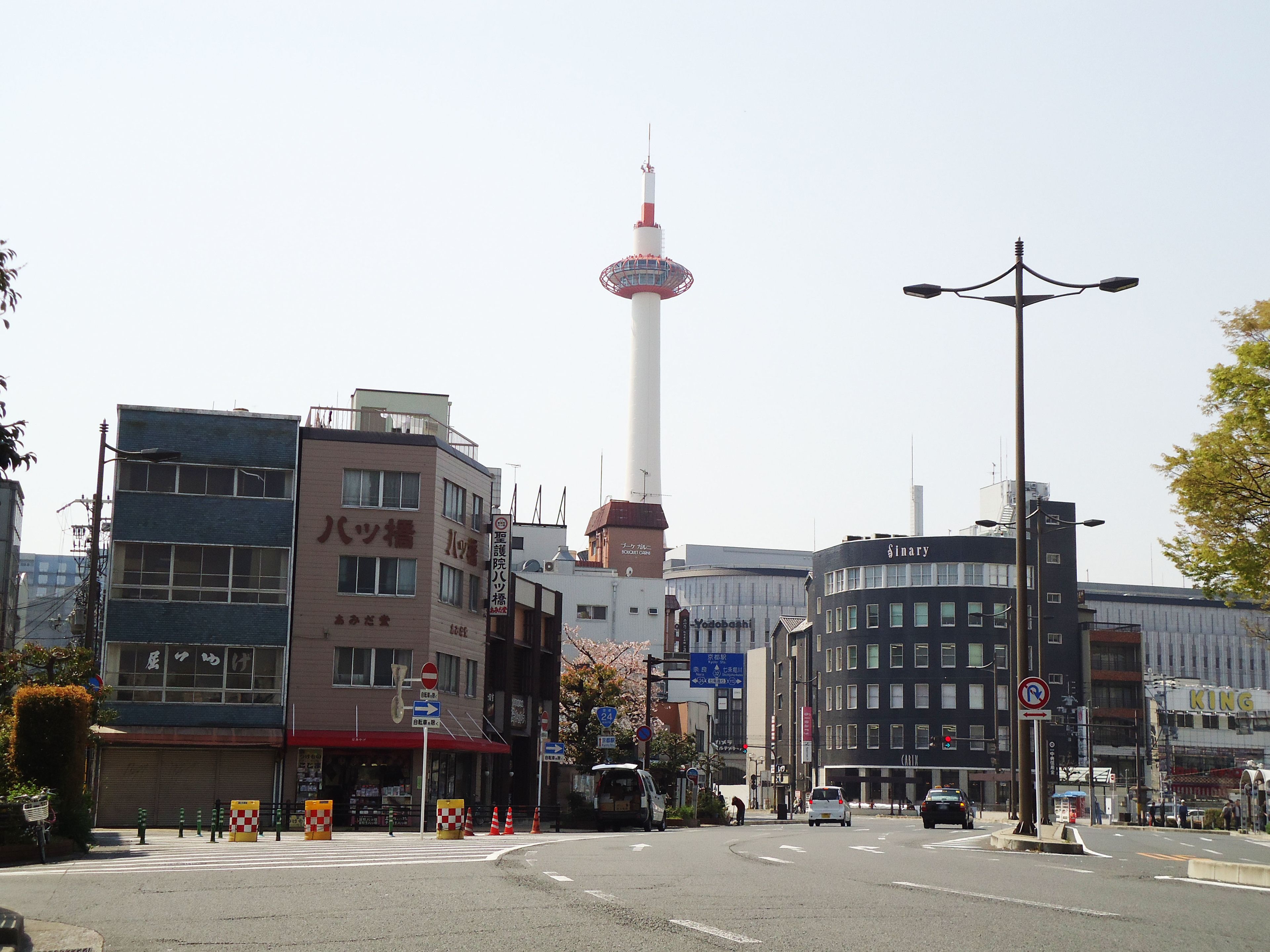 A street view with buildings, a tower, and a street sign.