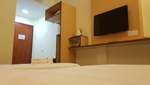 A hotel room with a bed, a television mounted on the wall, a wooden door, and a shelf with a kettle and other items. - Lipis Plaza Hotel (Kuala Lipis)