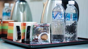 A tray with a coffee maker, two water bottles, a coffee pod, and colorful mugs. - Lipis Plaza Hotel (Kuala Lipis)
