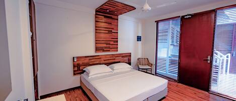 Un dormitorio moderno con cabecera de madera, una cama individual, ventilador de techo y un ventanal con persianas.