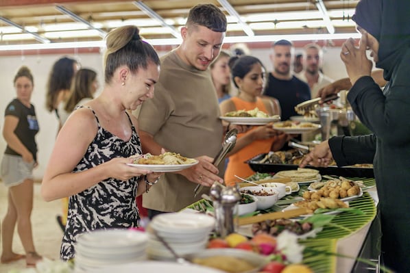 A buffet with various dishes and a group of people serving themselves. - Kinan Retreat (Fulidhoo)