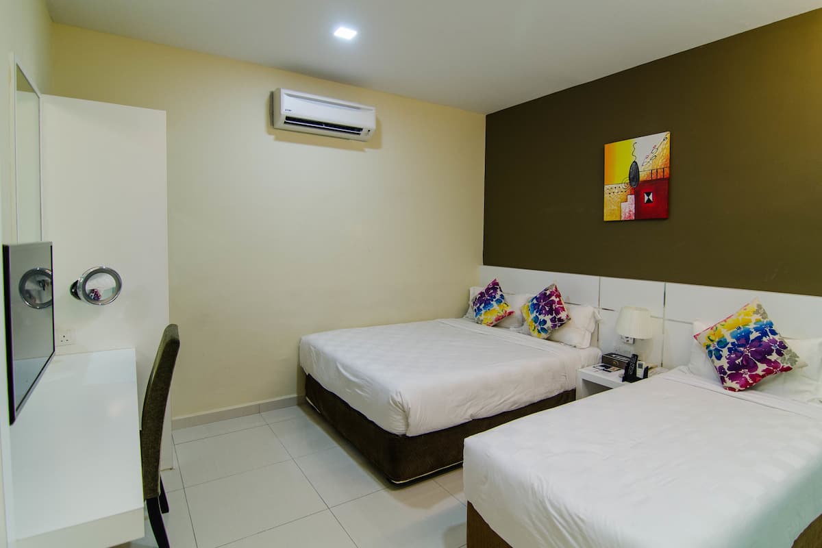 A hotel room with two beds, a desk, a chair, an air conditioning unit, and a painting on the wall.
