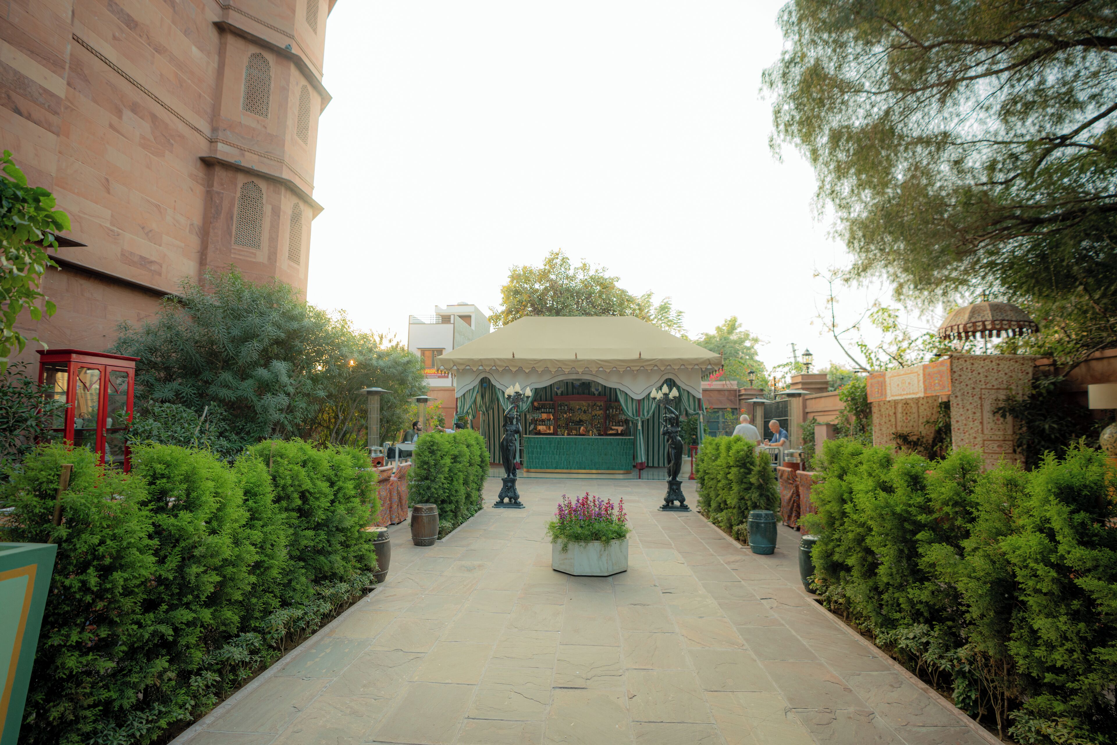 A courtyard with a central garden, stone pathway, and a building with arched windows.