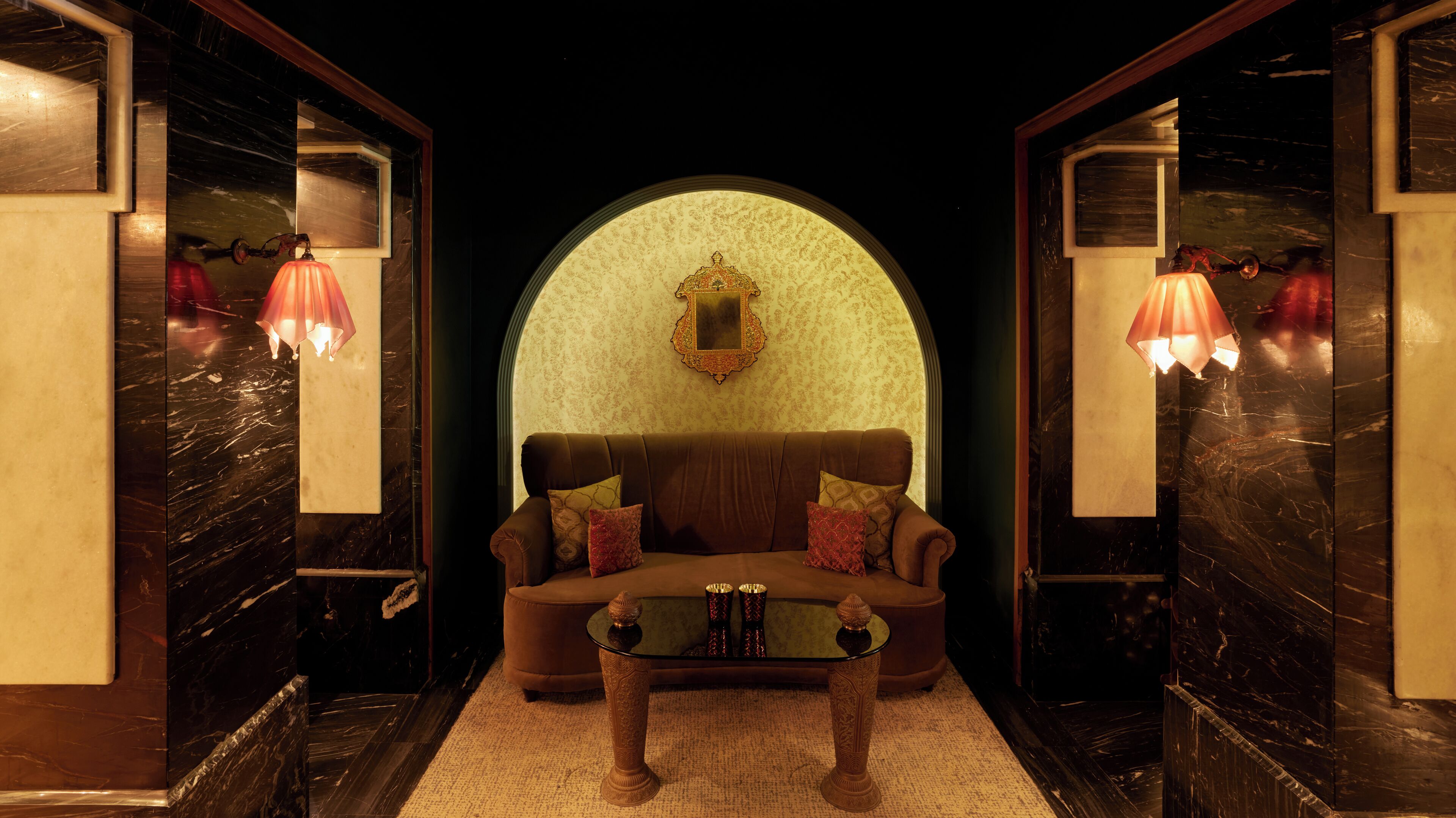 A luxurious room with a plush sofa, a glass coffee table, and ornate lamps.