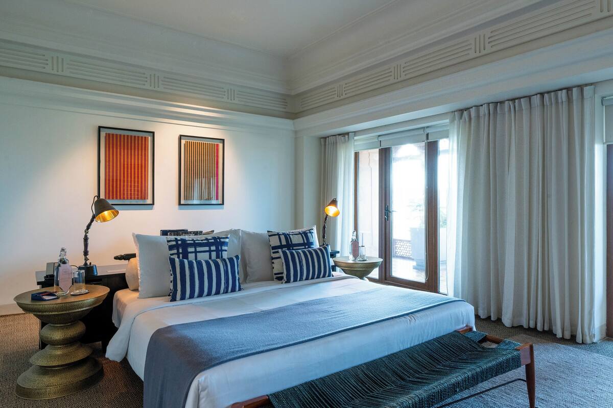 Une chambre d’hôtel avec un grand lit, deux tables de chevet, une lampe et une vue sur l’extérieur par la fenêtre.