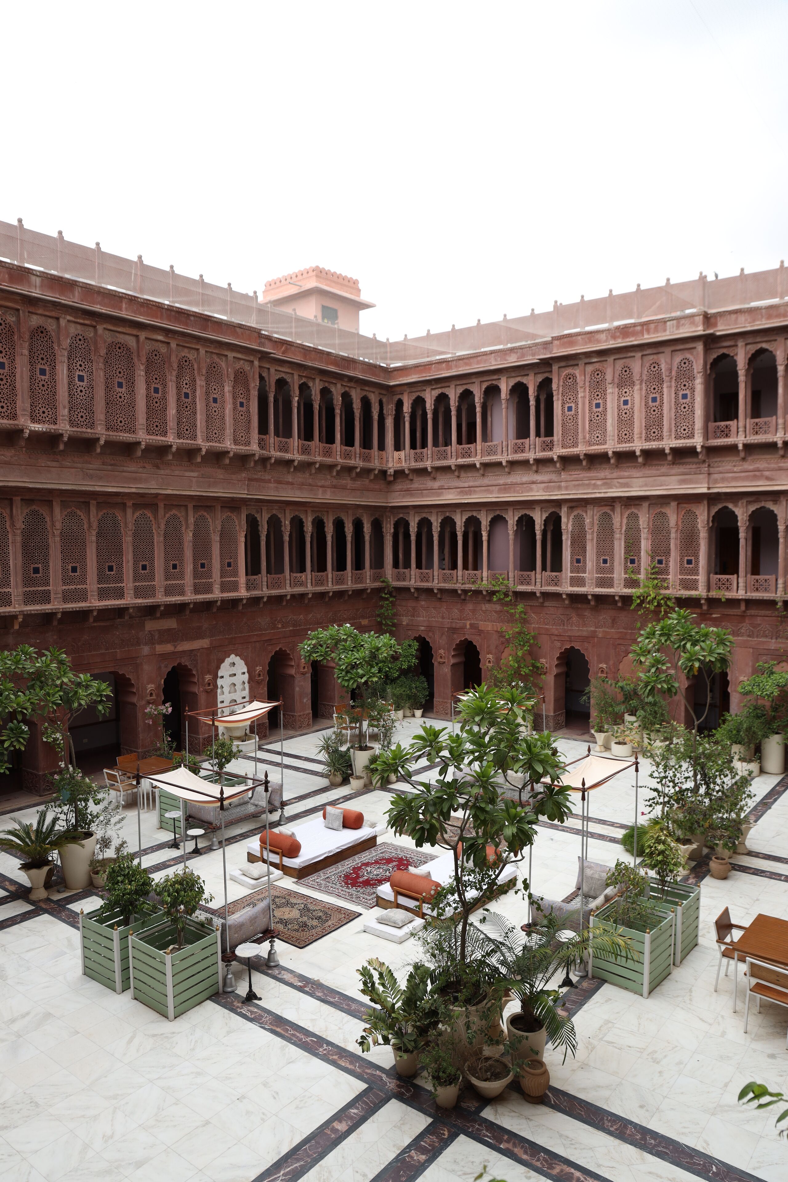 A courtyard with a red brick building, potted plants, and outdoor seating.
