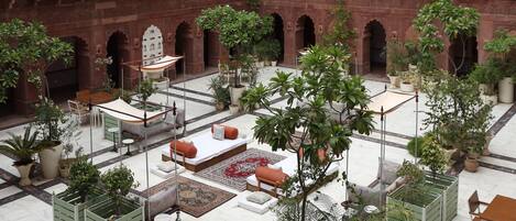 A courtyard with a red brick building, potted plants, and outdoor seating.